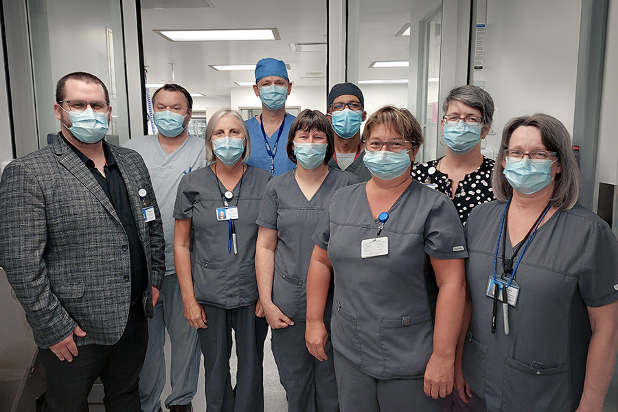 A group of employees standing proudly in front of the entrance to the completely renovated Medical Device Reprocessing Department (MDRD) at Campbellton Regional Hospital. In front, from left to right: Maxime Conrad Saulnier, Director of Hospital Activities, Elise Landry, Sylvette Bujold, Nadine Haché and Nicole Savoie. In the back: Robert Firth, Jason Lavigne, Derrick Maxwell, and Danielle Leblanc, MDRD Coordinator. 